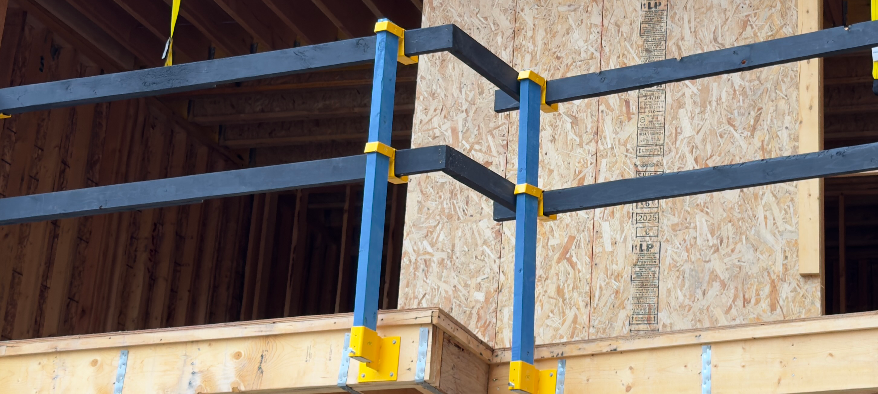 Construction worker on scaffolding at multi-story building with yellow safety railing